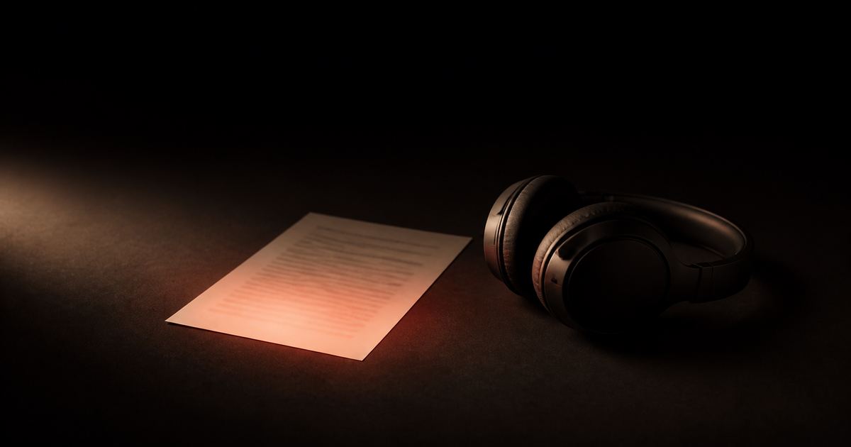 A phone playing an exported audio file next to a laptop showing a saved article, with a soft ember waveform between them